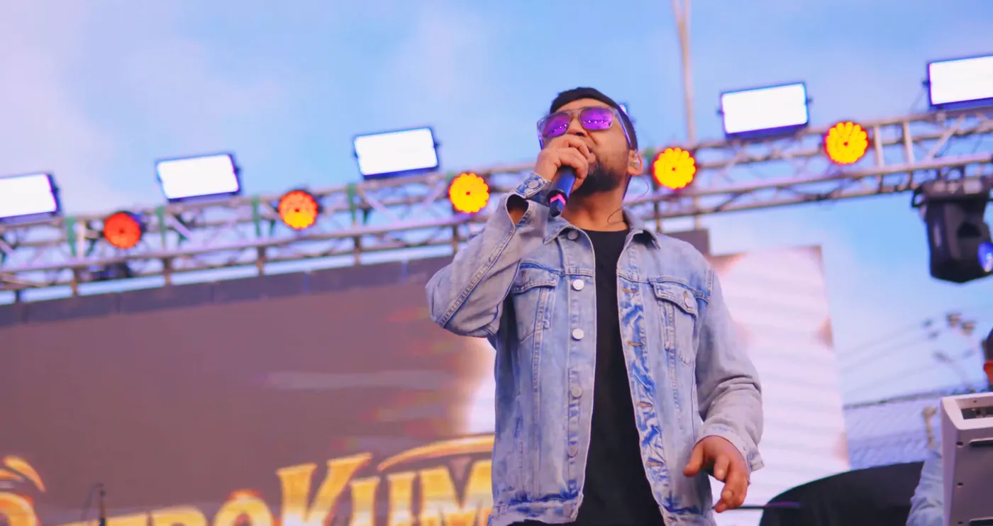 El vocalista con lentes de sol cantando frente a las luces del escenario